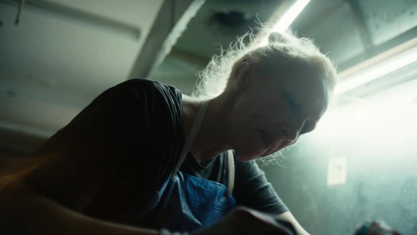 Close up of a sculptor brushing the surface of a statue in her workshop