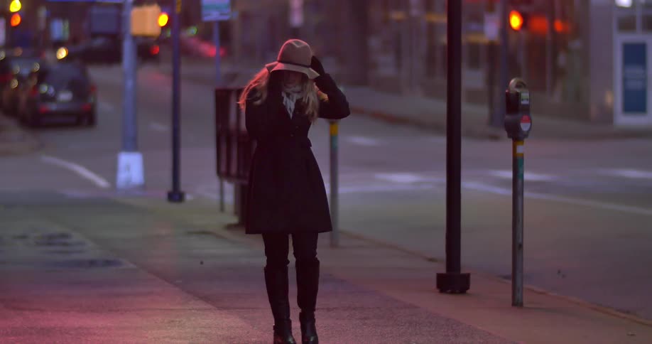 A woman walks down a city sidewalk while talking on the phone