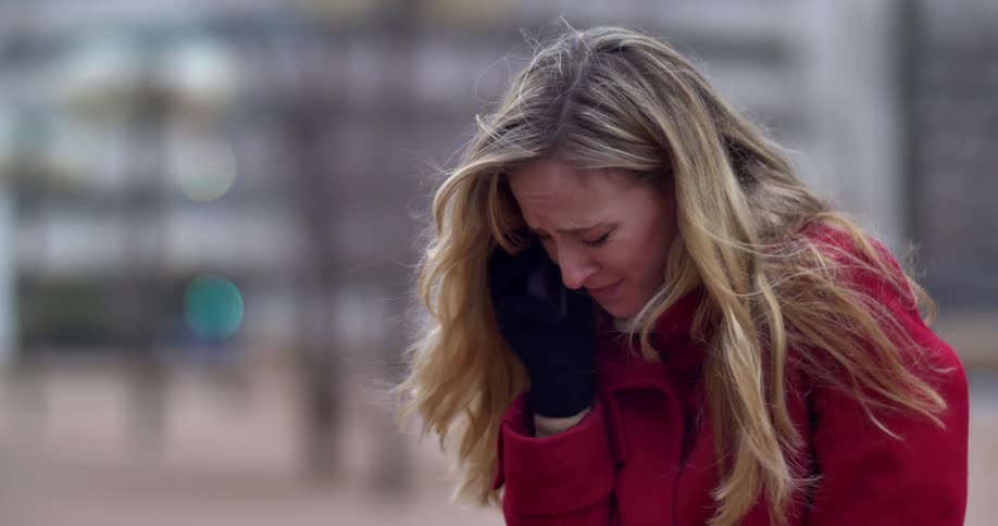 A woman cries as she talks on her cell phone outside