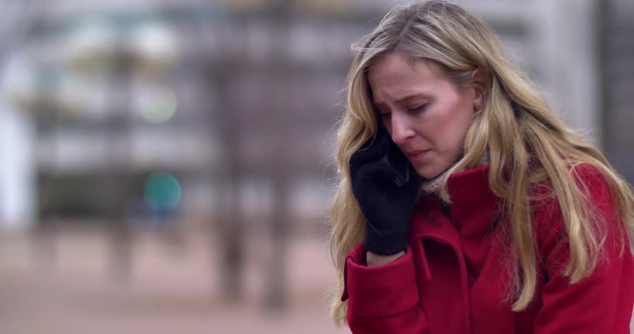 A woman crying and talking on her cell phone outside