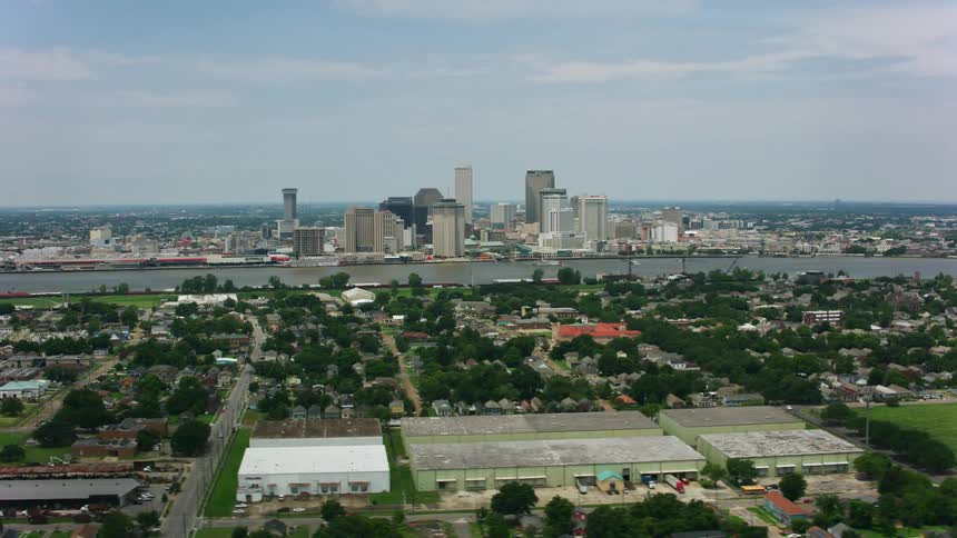 Aerial orbiting view of suburbs next to a river in front of the city downtown skyline