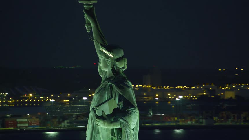 Aerial view of the statue of liberty in front of new york city at night