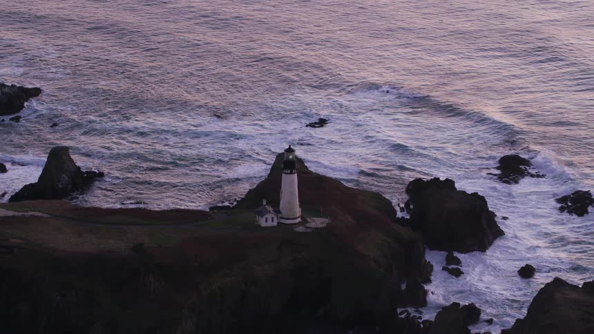 An aerial view of a lighthouse on rocky seaside cliffs