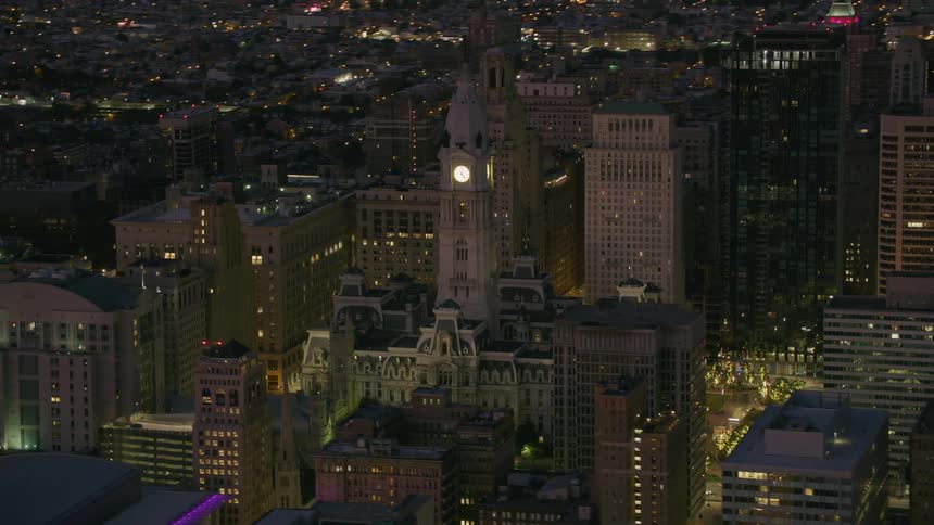 Aerial view of a clock tower among tall skyscrapers on the city at night