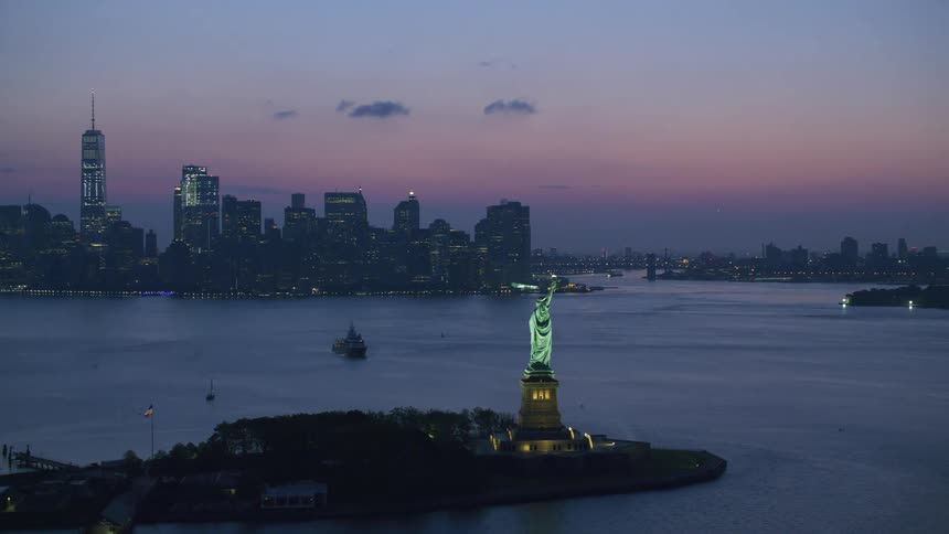 Aerial orbiting aerial view of the statue of liberty in front of the new york city skyline