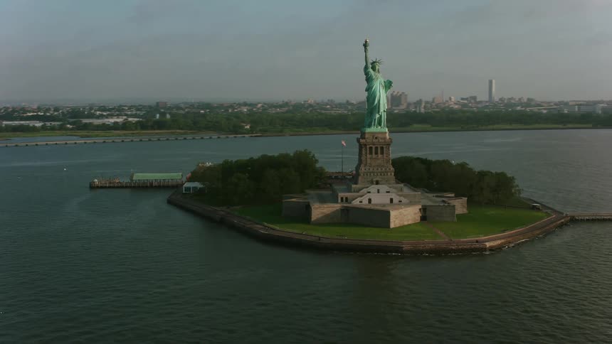 Ferry coasts past statue of liberty a distance from city skyscrapers