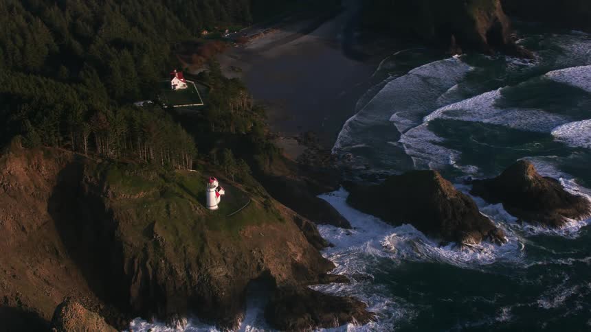 Aerial view of a lighthouse on the cliff over the coast next to the ocean