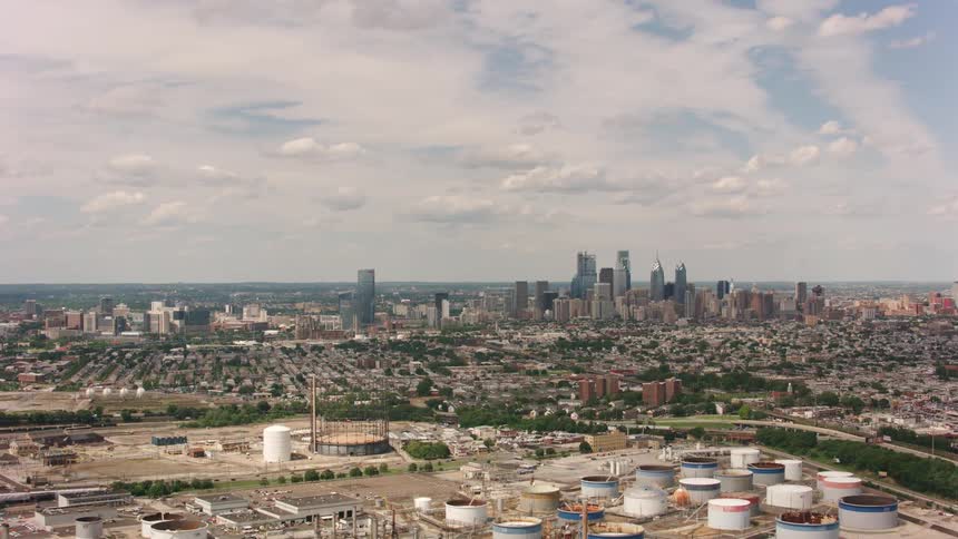 An aerial of factory buildings on the outskirts of a metropolis city with tall buildings