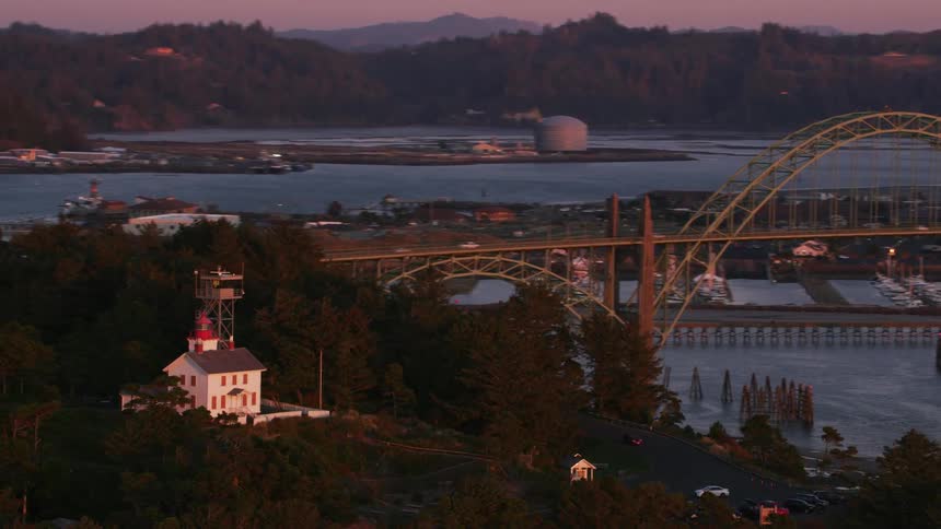 An aerial of a suburban coastal village with a large archway bridge built over a waterway