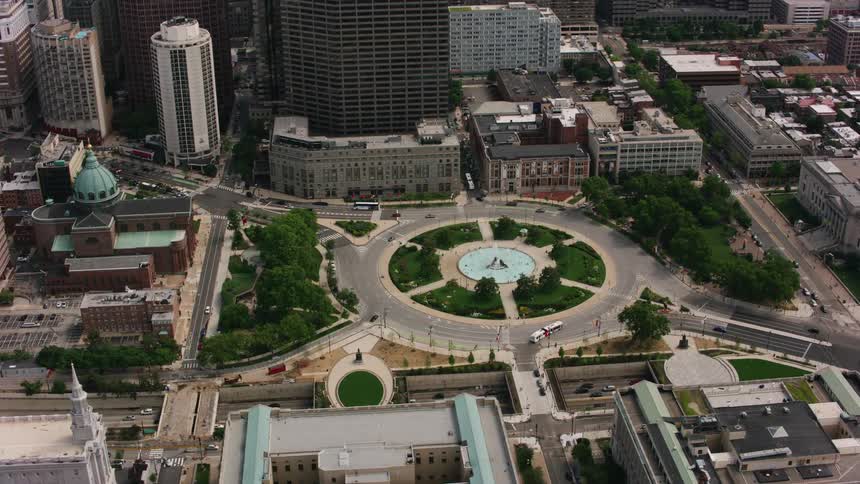 Traffic flows down highway between a church and a cathedral near road roundabout circling a fountain