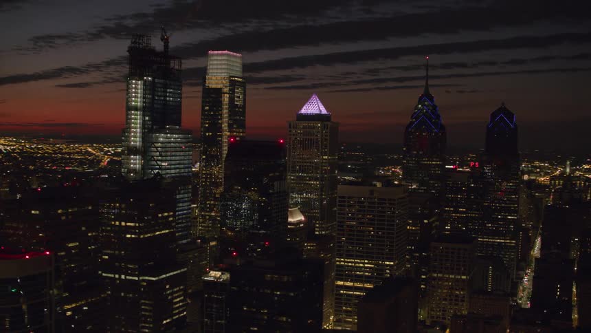 Several tall buildings in a metropolitan city are illuminated at night