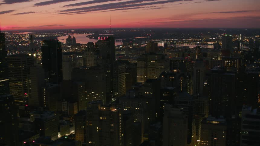 An aerial perspective of a dimlylit city skyline and skyscrapers at sunset
