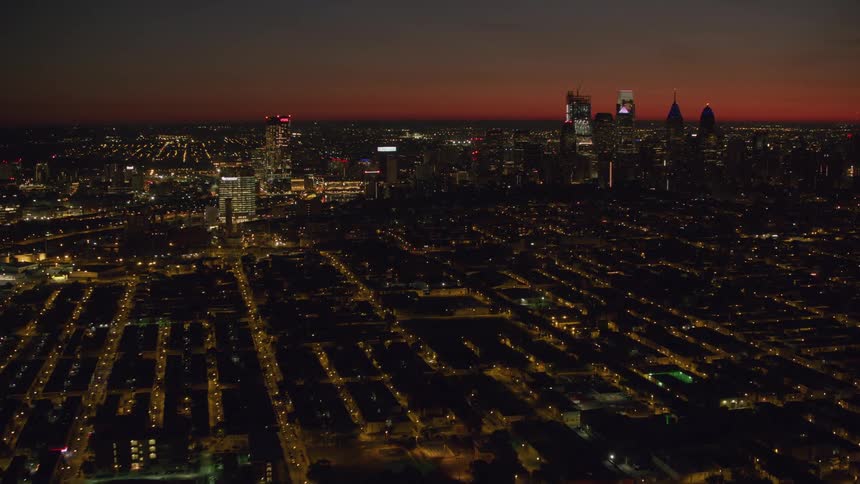 Nighttime aerial view of nyc skyline with red horizon and tall buildings in the distance