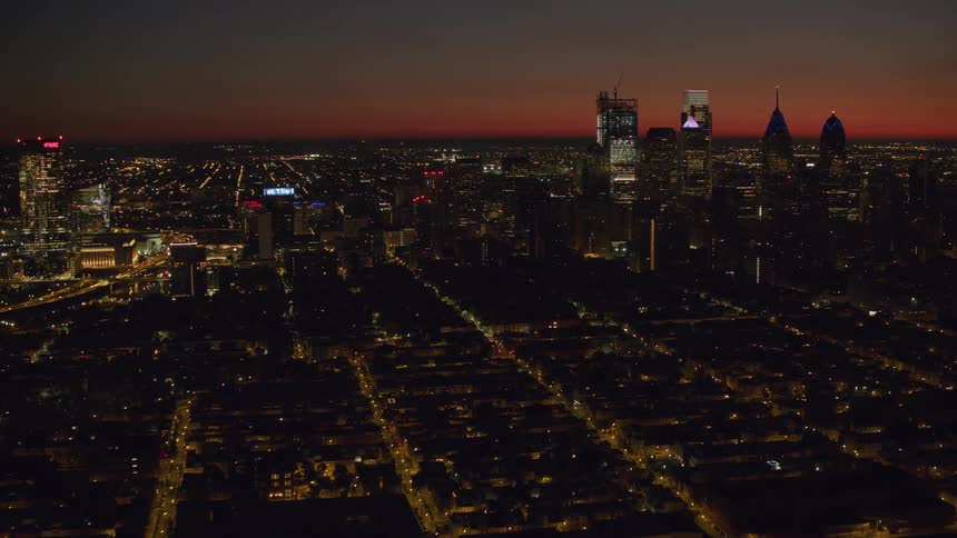 An aerial view of a litup city skyline and skyscrapers at night