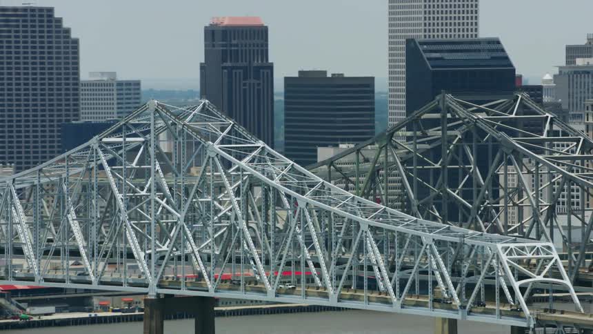 An aerial shot of two metal bridges over a river in front of city towers
