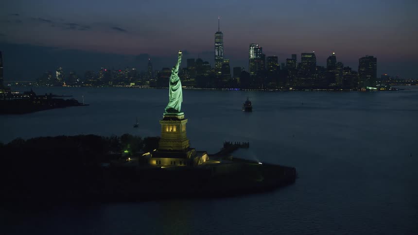 An aerial view going past the statue of liberty towards new york