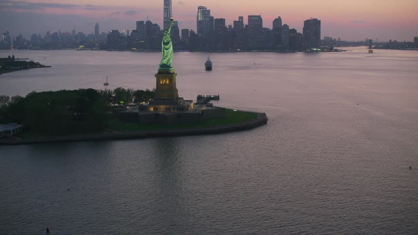Aerial view statue of liberty on liberty island and city skyline at sunset
