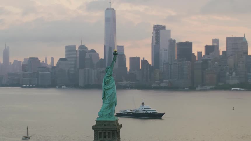 An aerial sunrise view of the statue of liberty with manhattan island in the background