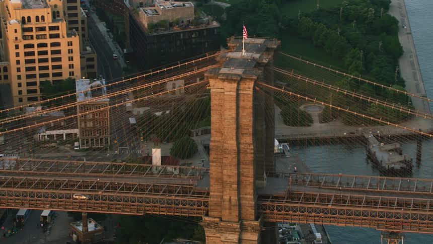 Aerial view of the american flag waving over the brooklyn bridge at evening