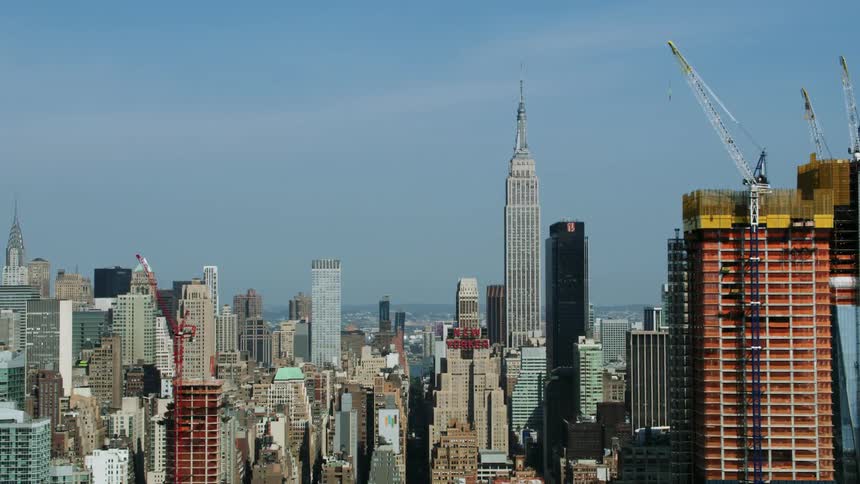 A cityscape with buildings of several shapes and sizes including skyscrapers under construction