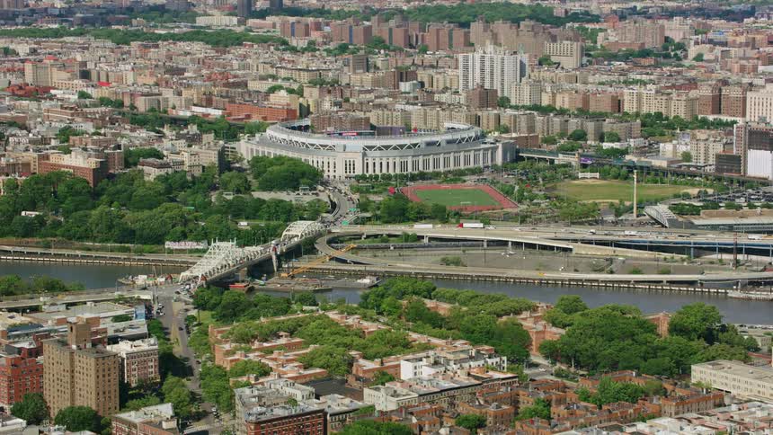 An aerial of a large city with tall buildings and a bridge going over a river with boats on it