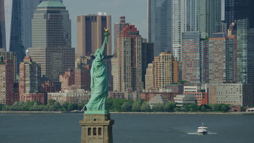 Aerial orbiting aerial view of the statue of liberty in front of the new york city skyline