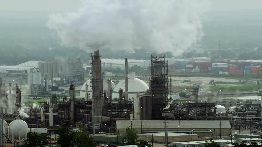 Smoke rise from manufacturing plants surrounded by woods on foggy day