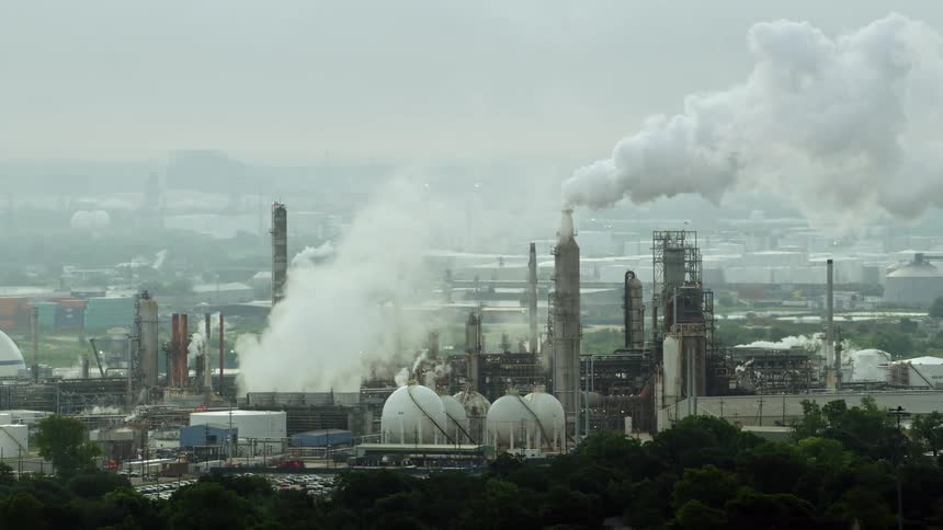 An aerial shot of urban factories bellowing smoke