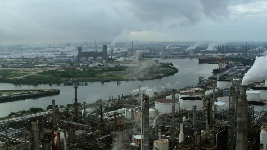 An aerial shot of an urban area with many smoking factories along a river