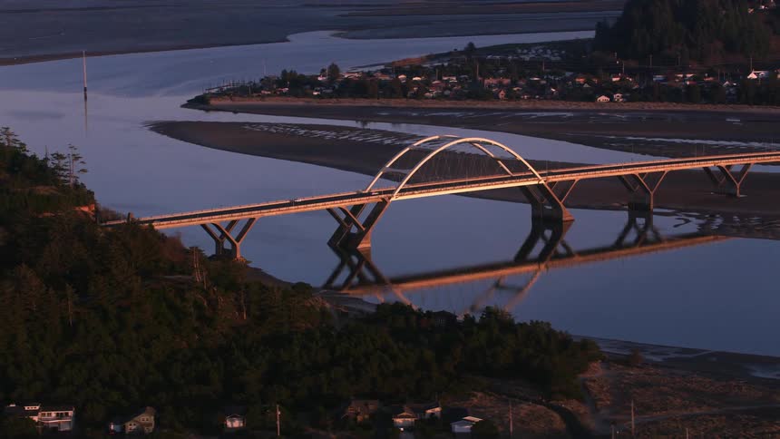 An aerial of a suburban neighborhood near a river with a large arch bridge going over the water
