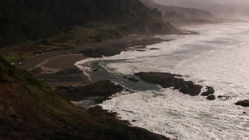 A rocky coastline including a small beach is hit by a stormy sea