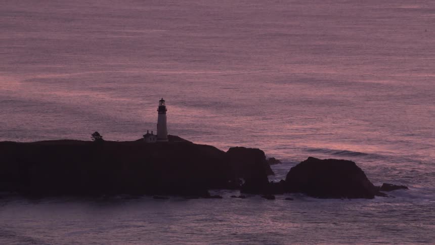 An aerial view of a lighthouse on cliffs near the ocean