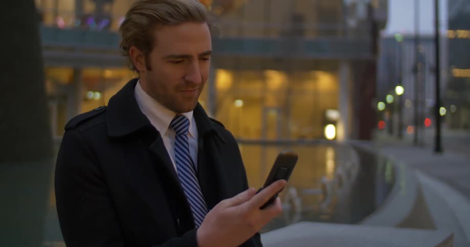 A man standing outside in the city using his cell phone
