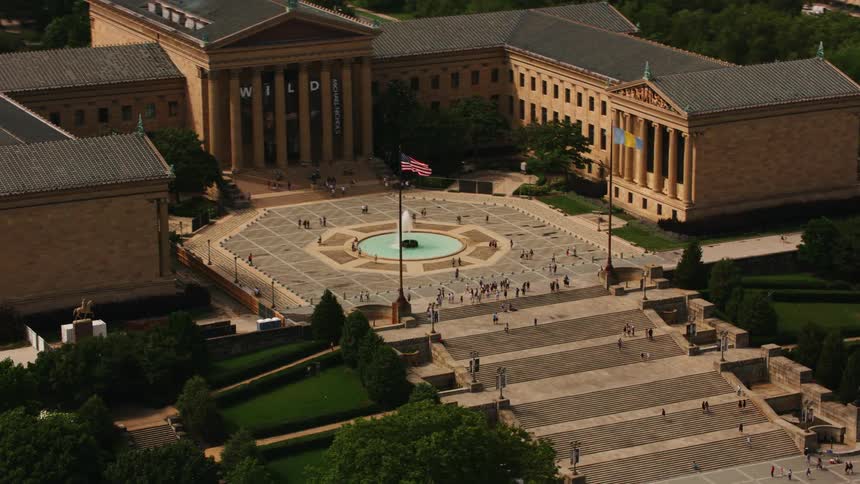 People hang out along the steps and around a fountain outside a building