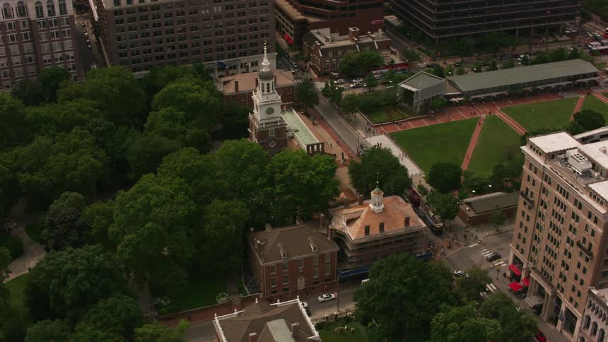Pedestrians and vehicles move between church and park in center of city