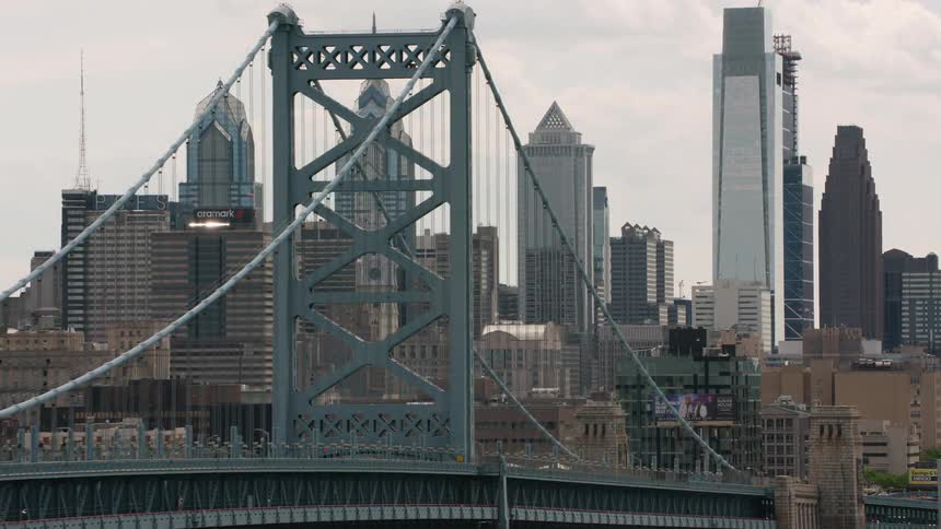 A suspension bridge in front of high rise office buildings in a city