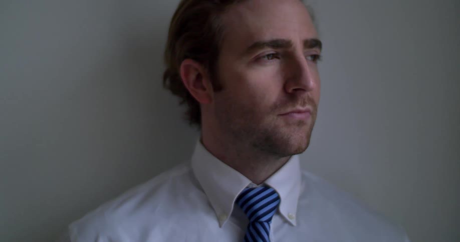 A man is leaning against the wall looking around