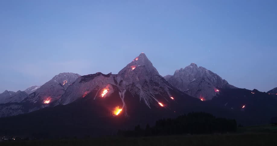 A mountain range with several fires below the snow line