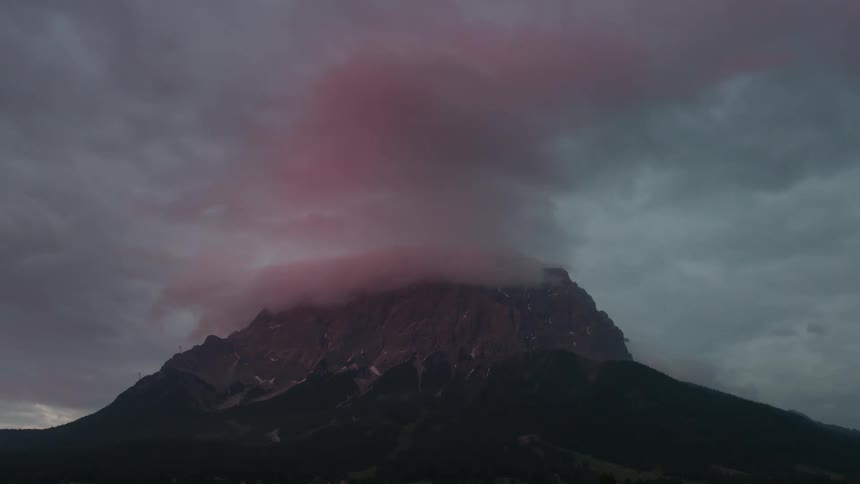 The last rays of sun hit the clouds on the Wetterstein mountain range with Zugspitze