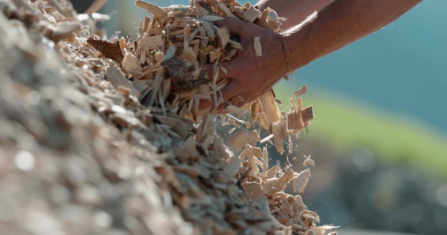 A man grabs a handful of mulch from a pile