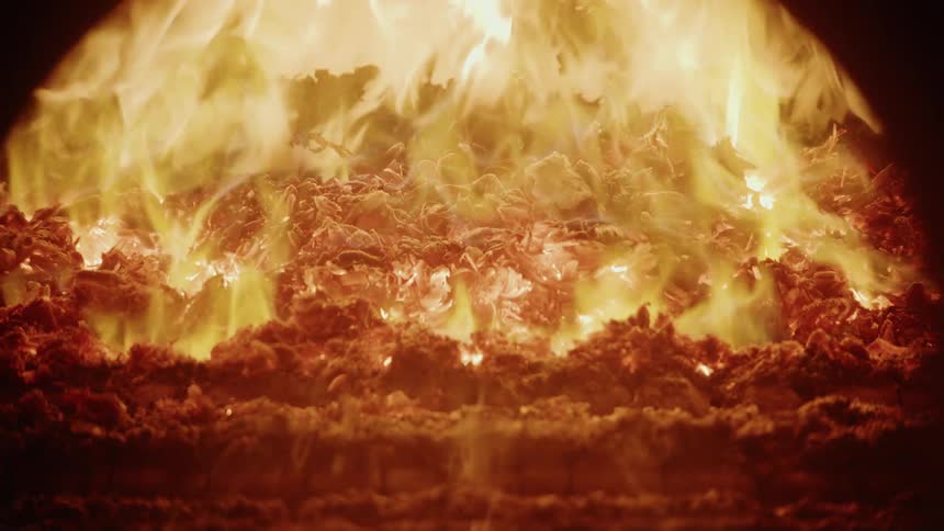 Fire and flames rise from the burning ashes as the fireplace glows