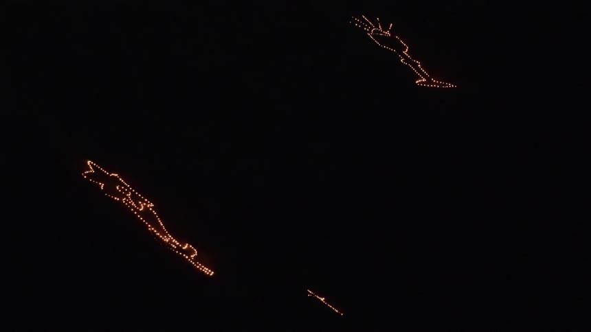 The light of fire flames in the shape of designs glow on a mountainside in the darkness of night