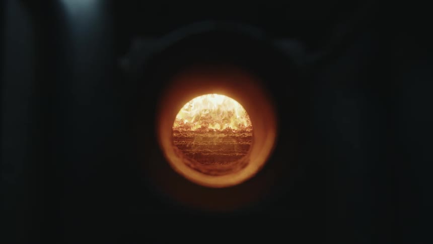 A circular entrance to a furnace opening and closing while the fire inside burns