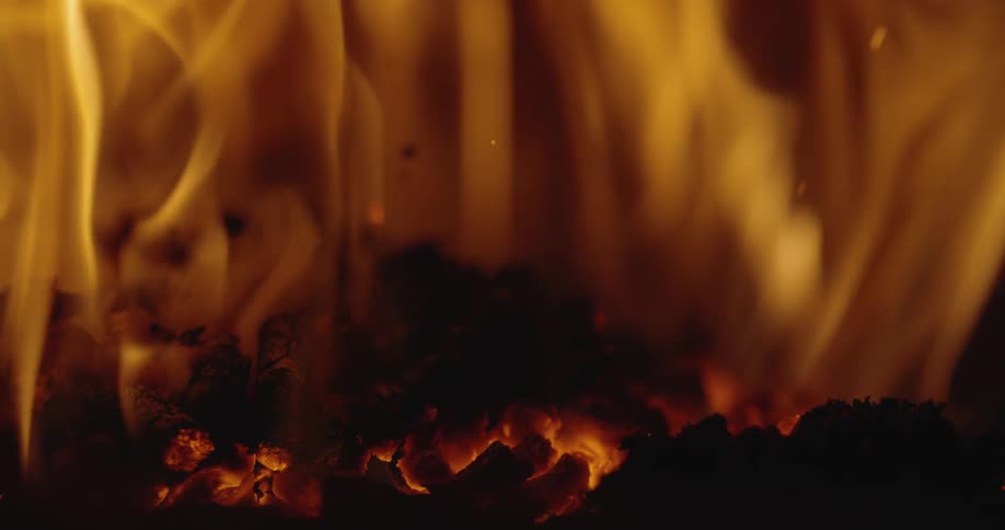 Fire and flames rise from the burning ashes as embers float upwards