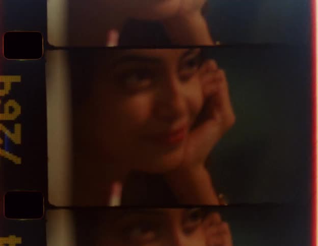 Woman smiles while leaning her chin on her palm and gazing across