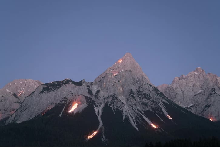 Drawings in fire appear on the side of mountains as the day progresses