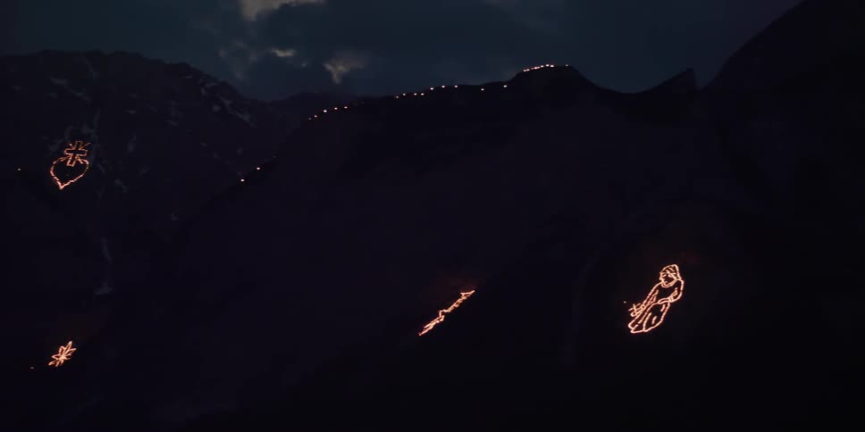 Lights outline religious symbols on mountainside at night