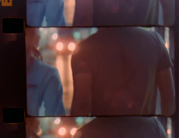 A man and woman hold hands as they walk down a city street
