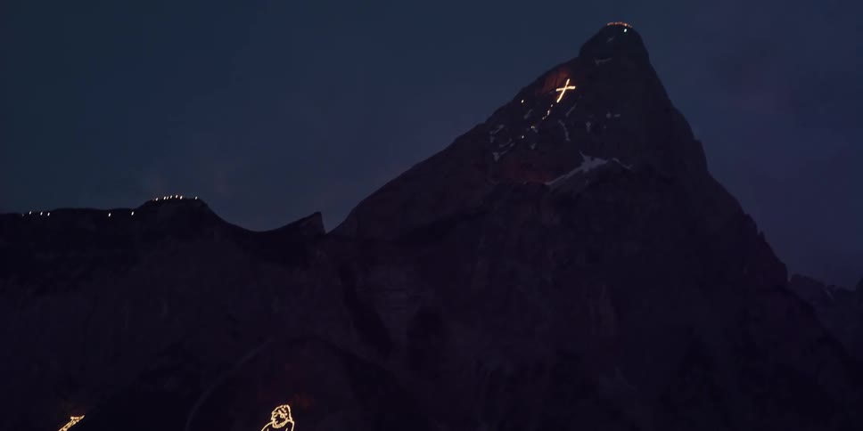 Lights form religious shapes on mountain sides at night