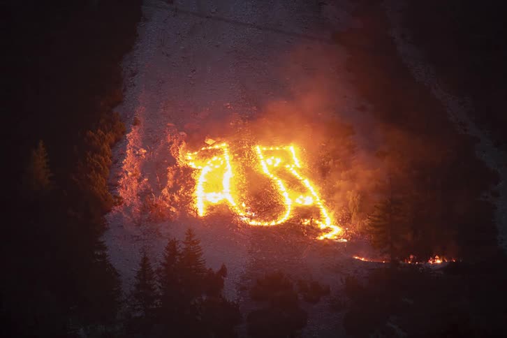 Flaming objects are set up to form a pattern on the side of a mountain